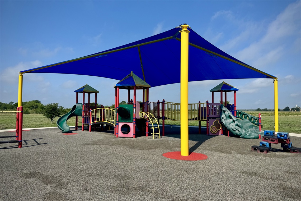 Colorful playground with a shade canopy, slides, and play structures.