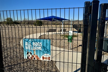 Fenced dog park entrance with a sign that reads 