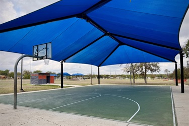 Basketball court with a blue shade structure.