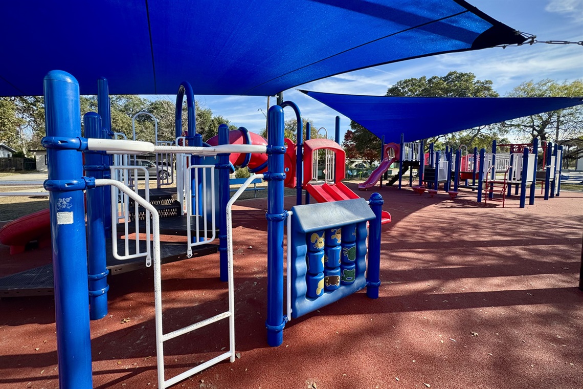 Red, white, and blue playground with multiple structures and shade canopies.