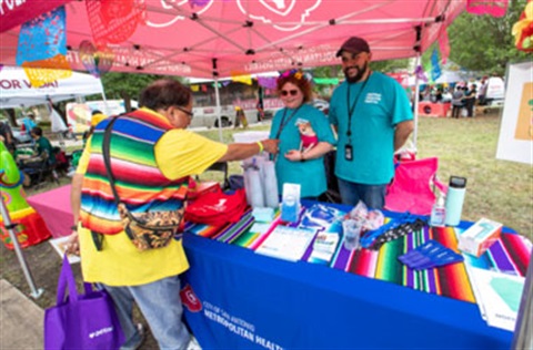 A couple stands under a tent with a table displaying various health information.
