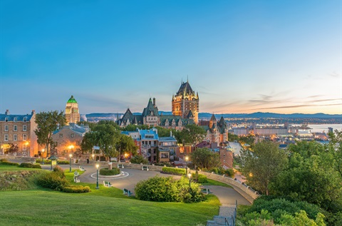 Sunset view of historic Château Frontenac Hotel and green park in Quebec City, Canada.