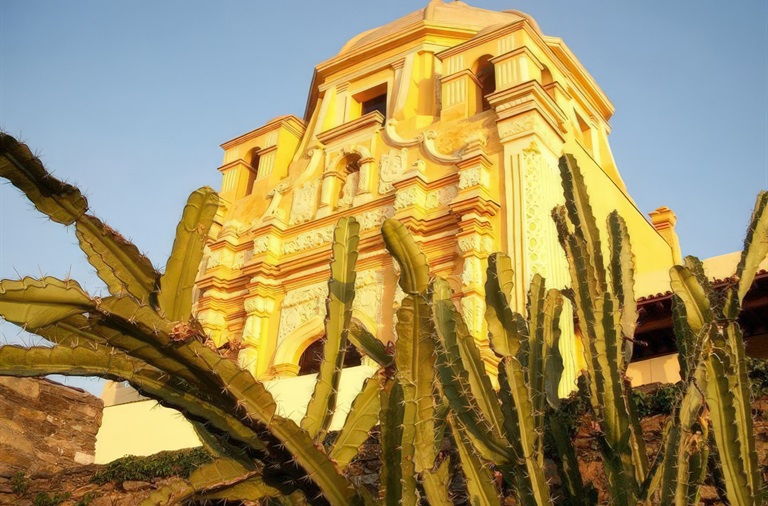 Angled daytime image of Museo del Obispado and cacti in Monterrey, Mexico.