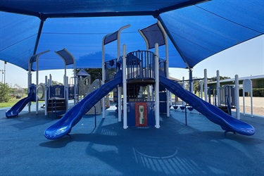Blue playground with slides and climbing structures under a large blue canopy.